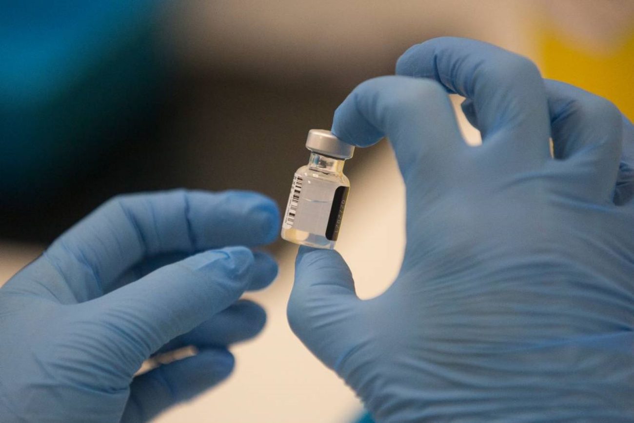 A worker holds a bottle of the Pfizer-BioNTech COVID-19 vaccine. GRAEME ROBERTSON AP