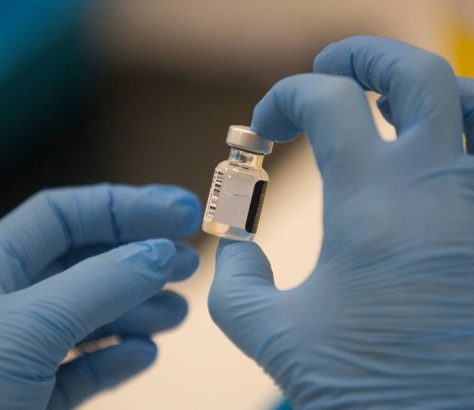 A worker holds a bottle of the Pfizer-BioNTech COVID-19 vaccine. GRAEME ROBERTSON AP