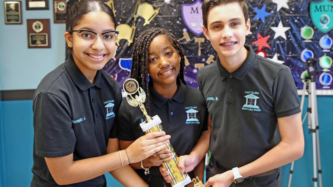 Jocelyn Hernandez, Gabriella Vega and Maurits Acosta hold one of the awards they won for an environmental project, on June 9, 2021. They are Miami Lakes Middle School students who proposed flood prevention legislation to the town council after Tropical Storm Eta flooded parts of the west Miami-Dade town, including their school auditorium